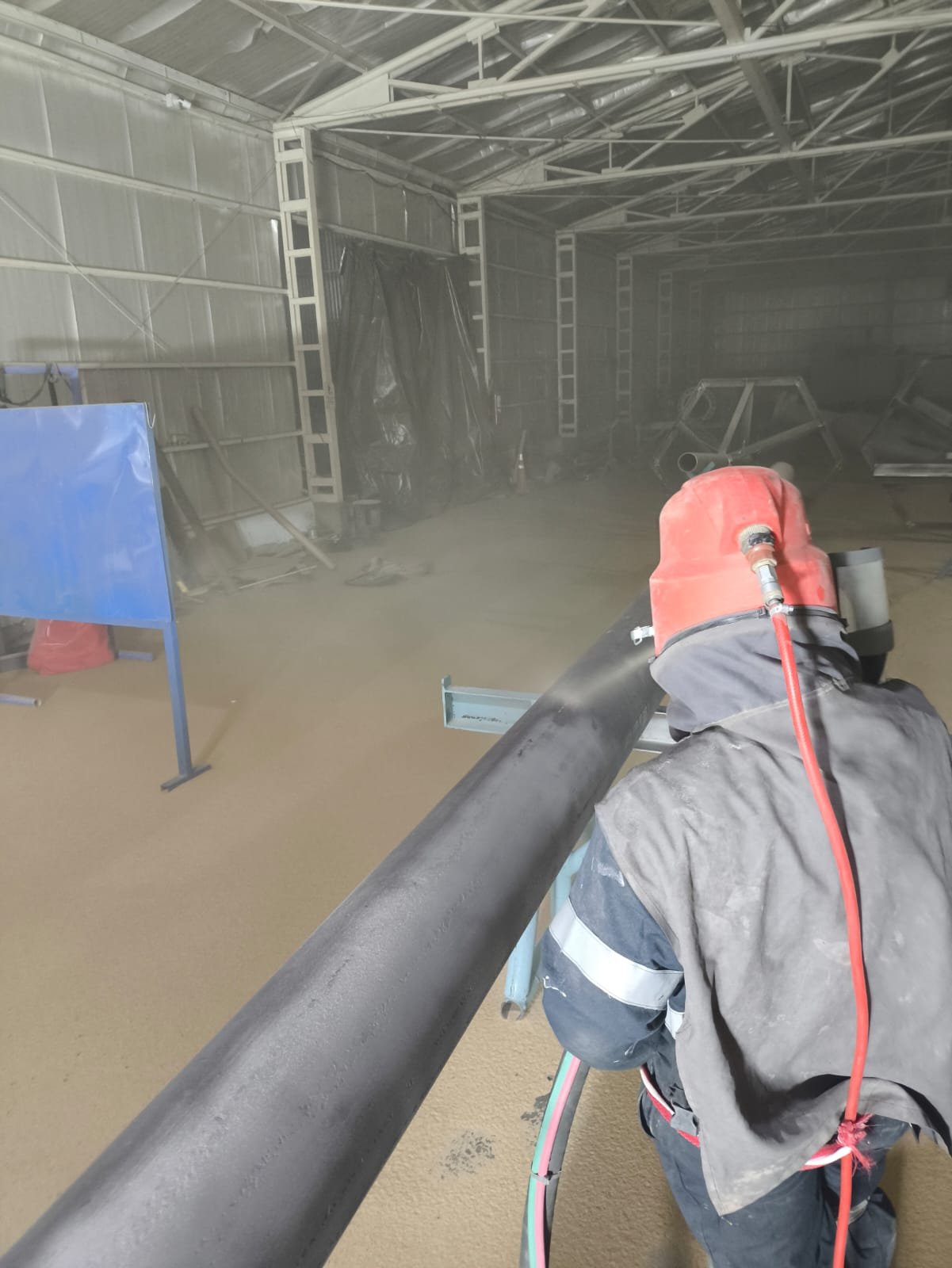 Operario realizando arenado sobre una cañería industrial